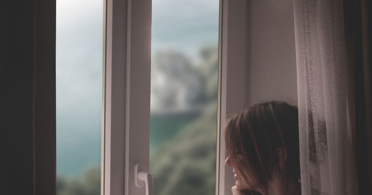 Woman seated by a window in quiet reflection