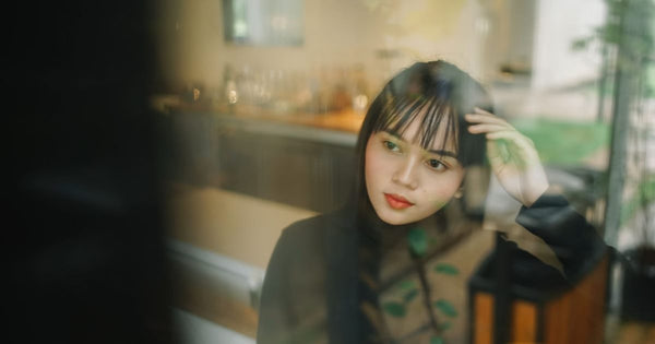 Woman reflecting while seated near a window